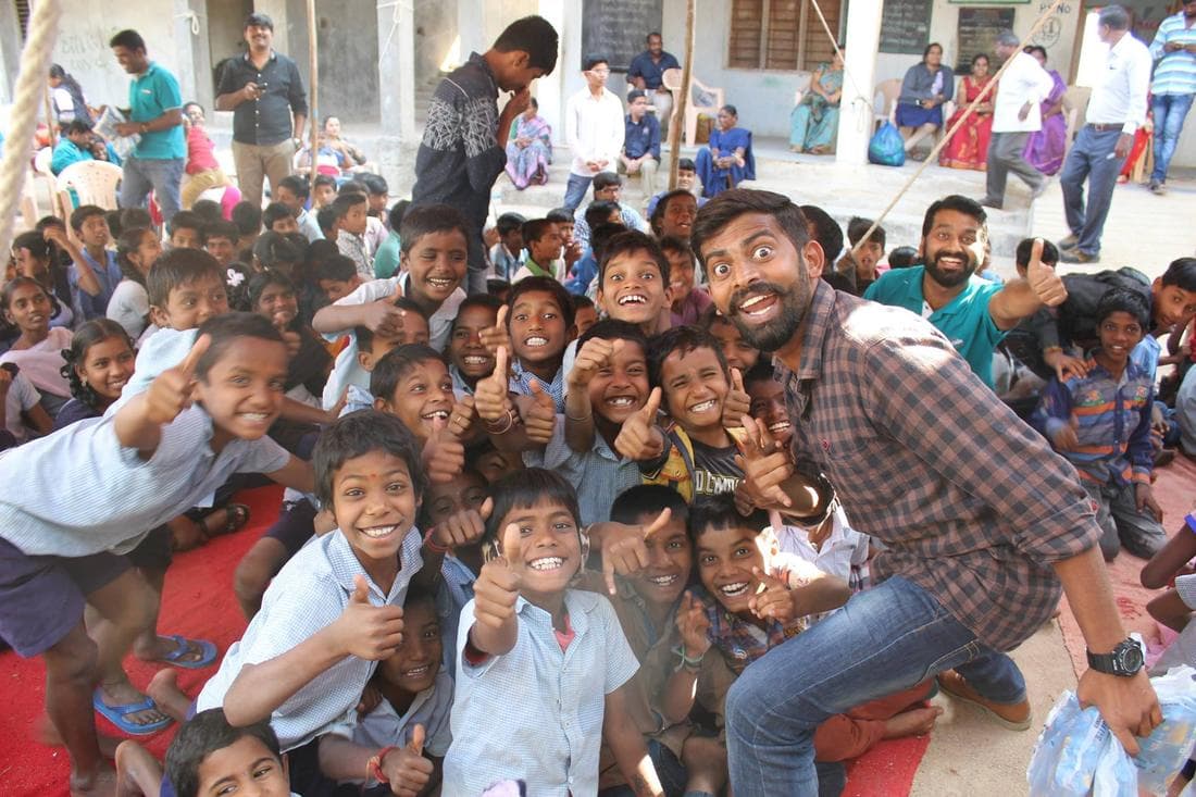 Primary school children seated in a school courtyard with TechieRide volunteers among them