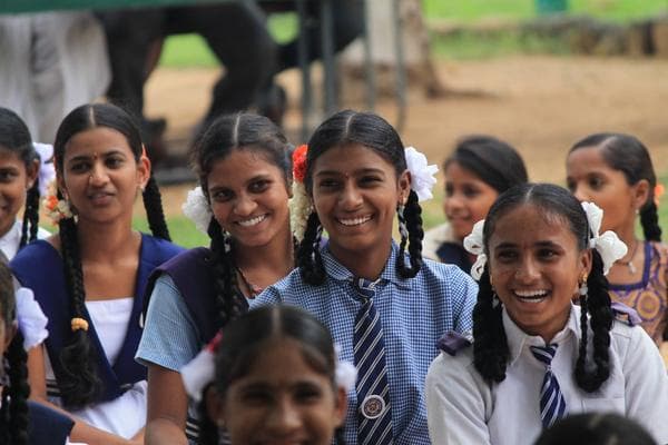 Government school students in uniform seated at an outdoor event