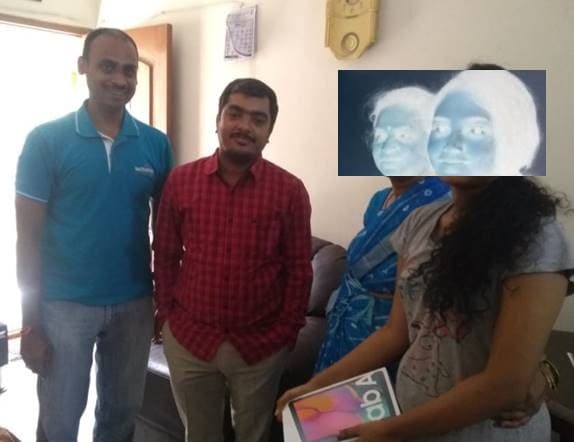 A student receiving a tablet at home, handed over by TechieRide volunteers